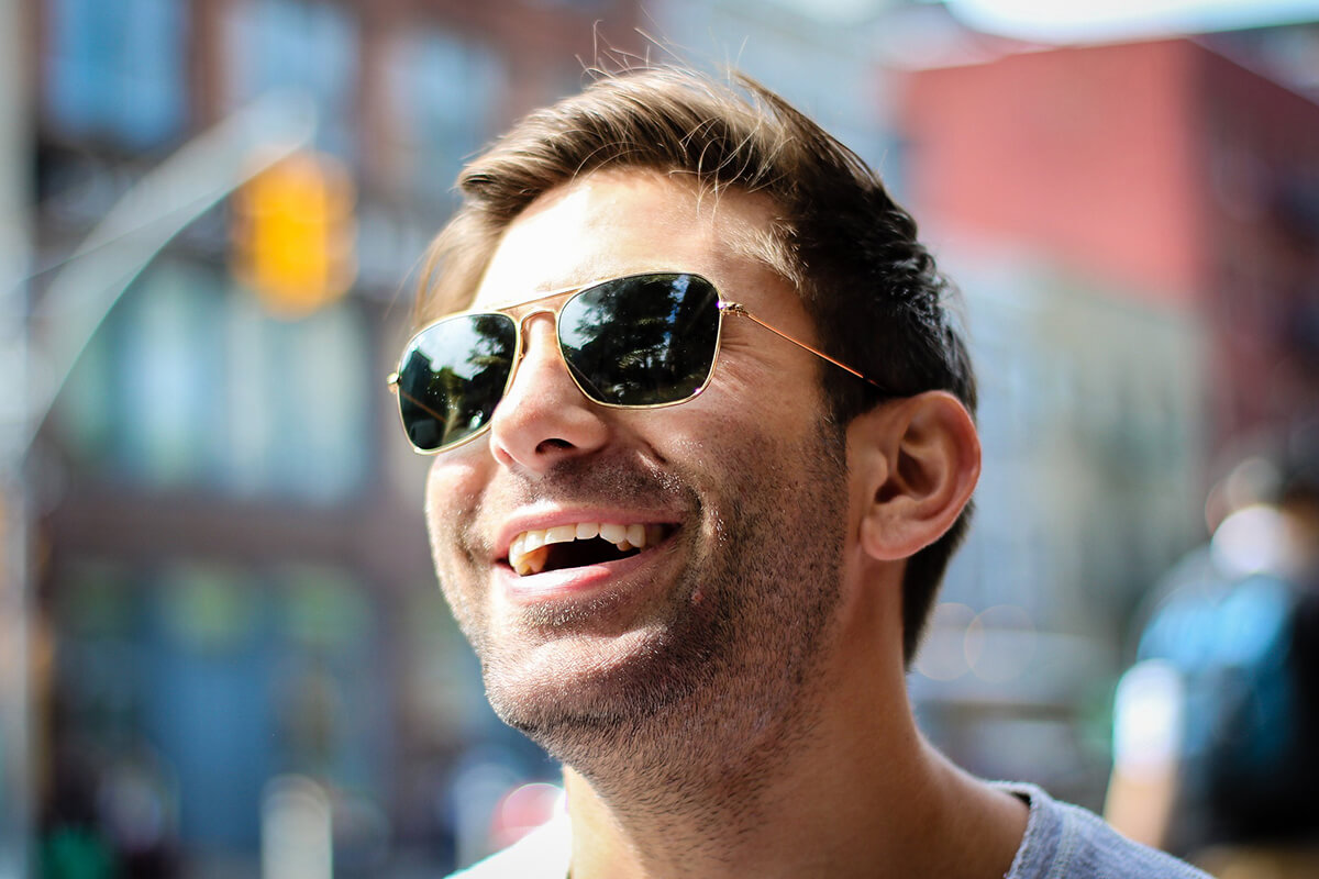 Lachender Mann mit Sonnenbrille und schoenen Zaehnen