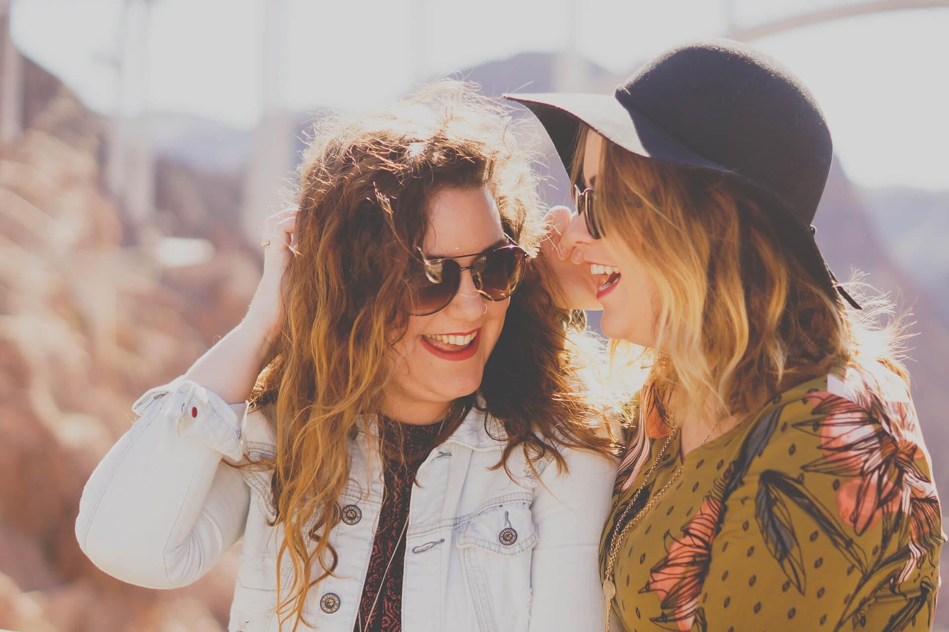 Zwei Freundinnen lachen in der Sonne mit schoenen Zaehnen