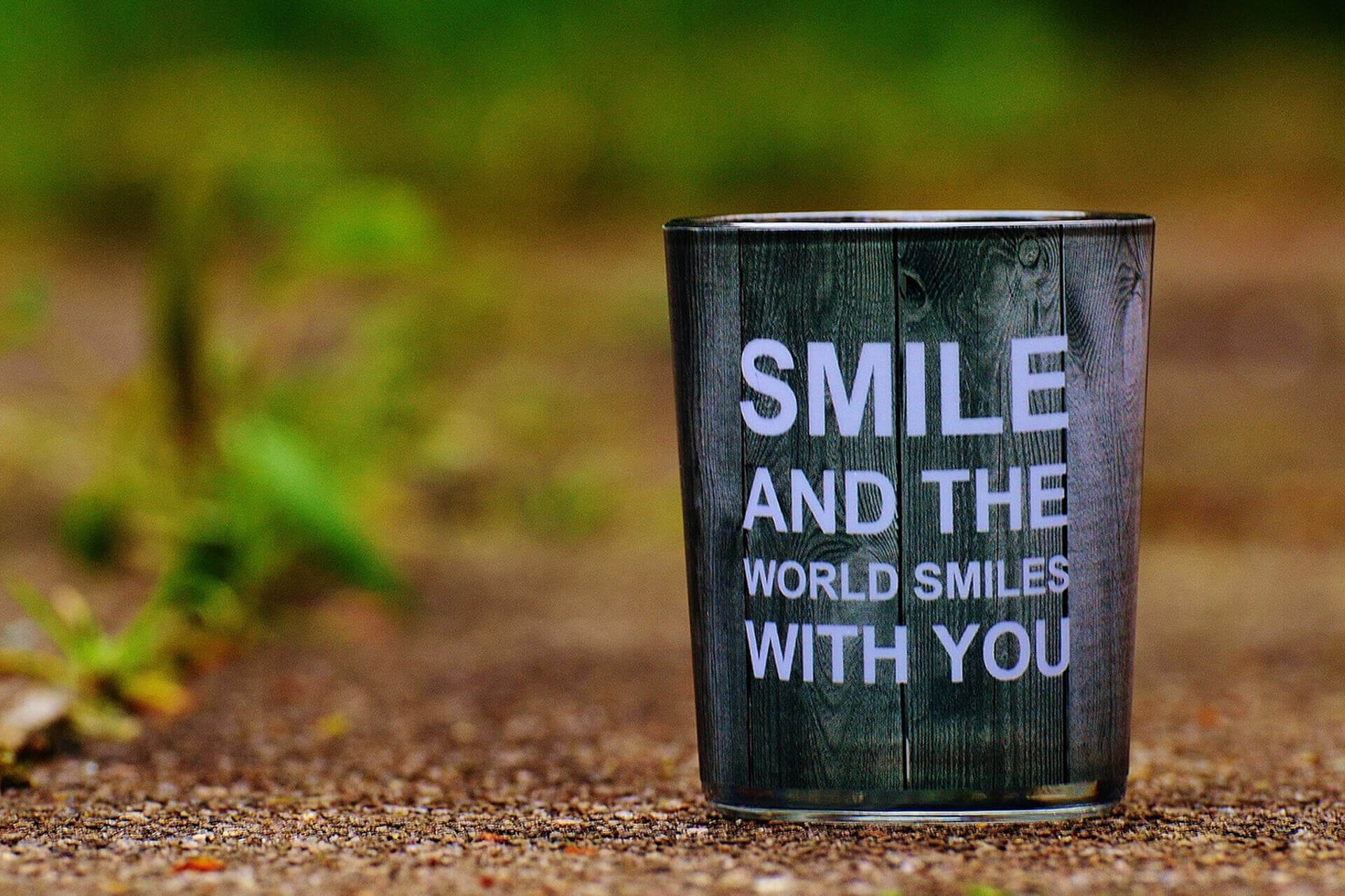 Becher vor Hintergrund mit Zitat SMILE AND THE WORLD SMILES WITH YOU