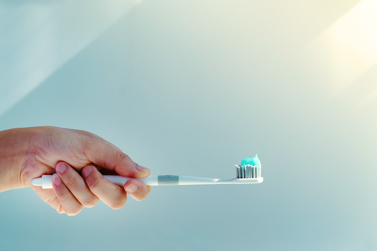 Zahnbuerste mit Zahncreme, die von einer weiblichen Hand gehalten wird